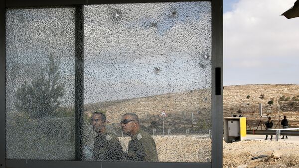 Members of the Israeli security forces walk past the shattered glass of the security post at the entrance to the West Bank settlement of Har Adar after a Palestinian opened fire on security personnel in a fatal attack before being shot dead - Sputnik International