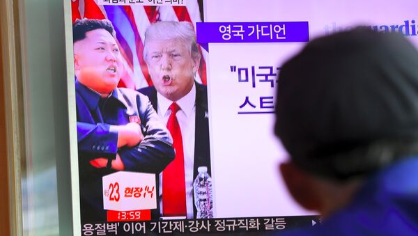 A man watches a television news programme showing US President Donald Trump (C) and North Korean leader Kim Jong-Un (L) at a railway station in Seoul on August 9, 2017 - Sputnik International