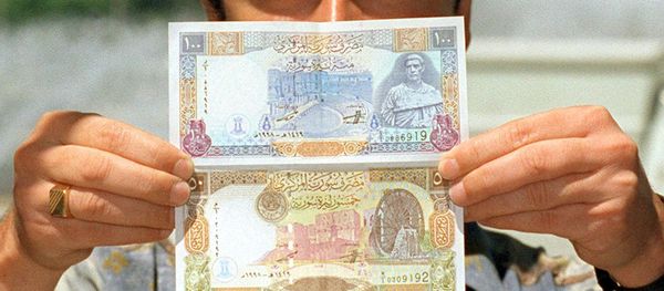 A Syrian man displays new 100 and 50 pound bills issued by the Syrian Central Bank. (File) - Sputnik International