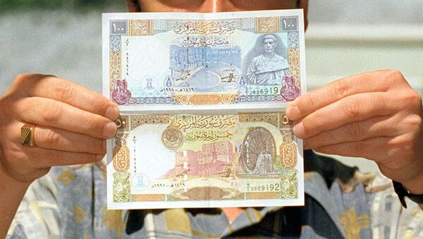 A Syrian man displays new 100 and 50 pound bills issued by the Syrian Central Bank. (File) - Sputnik International