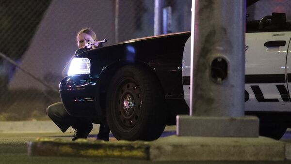 A police officer takes cover behind a police vehicle during a shooting near the Mandalay Bay resort and casino on the Las Vegas Strip, Sunday, Oct. 1, 2017, in Las Vegas - Sputnik International