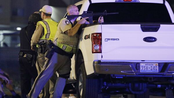A police officer takes cover behind a truck at the scene of a shooting near the Mandalay Bay resort and casino on the Las Vegas Strip, Sunday, Oct. 1, 2017, in Las Vegas - Sputnik International