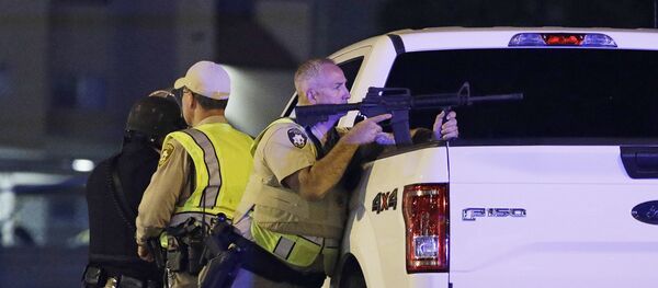 A police officer takes cover behind a truck at the scene of a shooting near the Mandalay Bay resort and casino on the Las Vegas Strip, Sunday, Oct. 1, 2017, in Las Vegas - Sputnik International