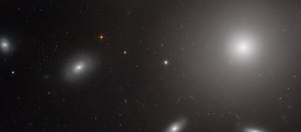 A photo of the center of the Coma Galaxy Cluster. The bright spherical shape is NGC 4874, a galaxy with an extremely powerful gravitational pull that is surrounded by globular clusters of stars. - Sputnik International