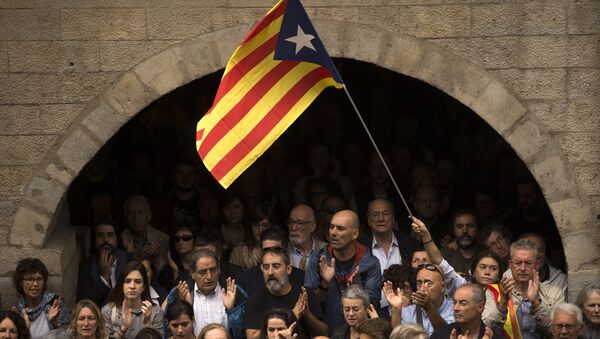 Catalan independence supporters, one waving an estelada, or Catalonia independence flag, applaud during a rally outside the city hall of Girona, Spain - Sputnik International