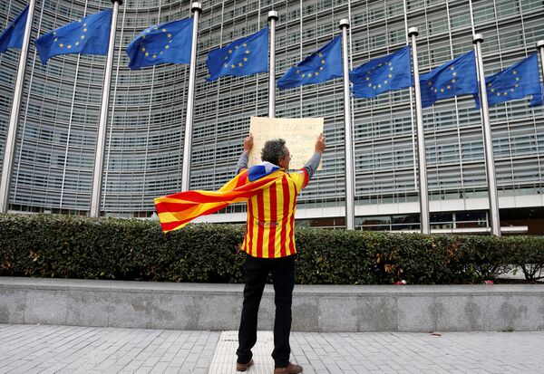 Catalan Raimon Castellvi, wearing a flag with an Estelada (Catalan separatist flag), holds a sign as he protests outside the European Commission in Brussels after Sunday's independence referendum in Catalonia, Belgium October 2, 2017 Catalan Raimon Castellvi, wearing a flag with an Estelada (Catalan separatist flag), holds a sign as he protests outside the European Commission in Brussels after Sunday's independence referendum in Catalonia, Belgium October 2, 2017 - Sputnik International