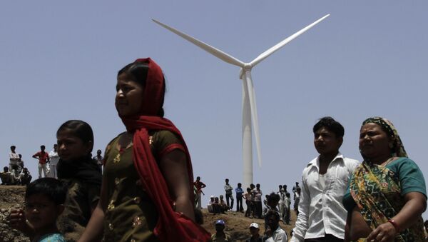 Indian villagers walk past a wind mill during the inauguration of ReNew Power's 25.2 MW wind farm near Jasdan town, about 200 kilometers (125 miles) from Ahmadabad, India. (File) - Sputnik International