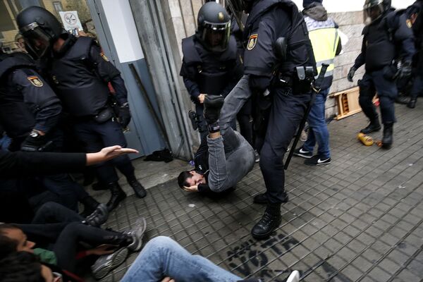 Spanish police officers drag a man as they try to disperse voters arriving to a polling station in Barcelona, on October 1, 2017 during a referendum on independence for Catalonia banned by Madrid Spanish police officers drag a man as they try to disperse voters arriving to a polling station in Barcelona, on October 1, 2017 during a referendum on independence for Catalonia banned by Madrid - Sputnik International