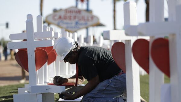 Greg Zanis writes the name of a victim of Sunday's mass shooting as he places crosses near the city's famous sign Thursday, Oct. 5, 2017, in Las Vegas. - Sputnik International