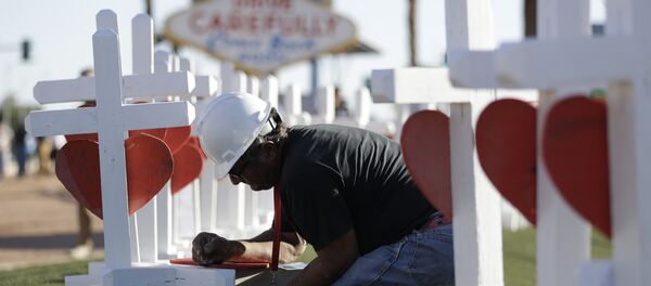 Greg Zanis writes the name of a victim of Sunday's mass shooting as he places crosses near the city's famous sign Thursday, Oct. 5, 2017, in Las Vegas. - Sputnik International