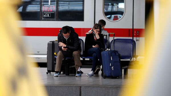 Passengers sit on a bench as they wait for a train during a strike of public transport service at Midi/Zuid railway station in Brussels, Belgium - Sputnik International