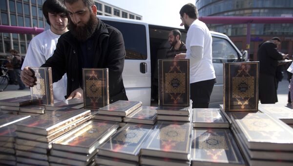 Members of a Muslim group pile Qurans while distributing copies of it at Potsdamer Platz in Berlin. (File) - Sputnik International