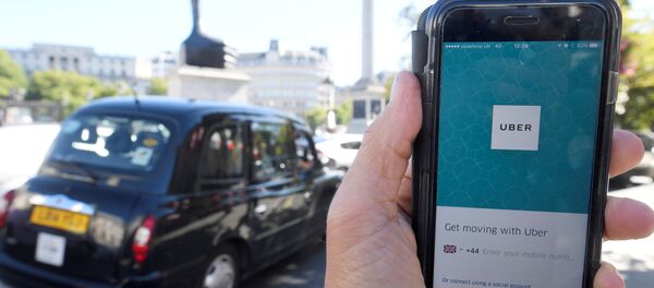 London taxi passing as the Uber app logo is displayed on a mobile telephone, as it is held up for a posed photograph in central London, Britain. (File) - Sputnik International