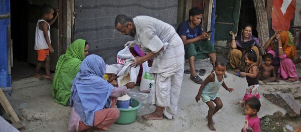 In this Tuesday, Sept. 12, 2017 photo, a Rohingya refugee distributes wheat, donated by locals, among other refugees at a camp for the refugees in New Delhi, India In this Tuesday, Sept. 12, 2017 photo, a Rohingya refugee distributes wheat, donated by locals, among other refugees at a camp for the refugees in New Delhi, India - Sputnik International