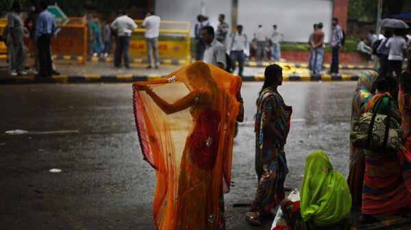An Indian woman adjusts her sari after she got wet in the monsoon rains in New Delhi, India, Wednesday, Aug. 7, 2013 - Sputnik International