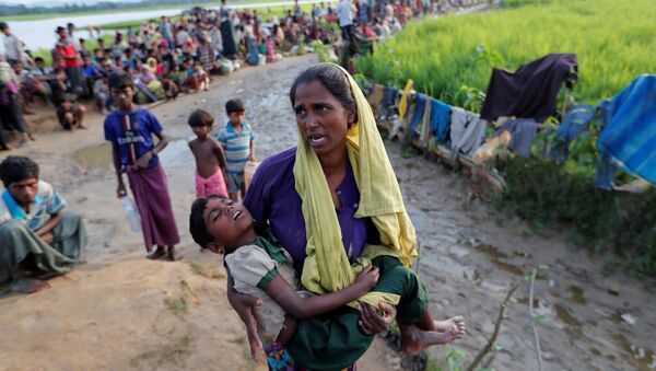 A Rohingya refugee woman who crossed the border from Myanmar a day before, carries her daughter and searches for help as they wait to receive permission from the Bangladeshi army to continue their way to the refugee camps, in Palang Khali, Bangladesh October 17, 2017 - Sputnik International