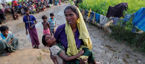 A Rohingya refugee woman who crossed the border from Myanmar a day before, carries her daughter and searches for help as they wait to receive permission from the Bangladeshi army to continue their way to the refugee camps, in Palang Khali, Bangladesh October 17, 2017 - Sputnik International