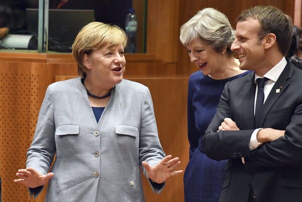 German Chancellor Angela Merkel, left, speaks with British Prime Minister Theresa May, center, and French President Emmanuel Macron prior to a round table meeting at an EU summit in Brussels on Thursday, Oct. 19, 2017. - Sputnik International