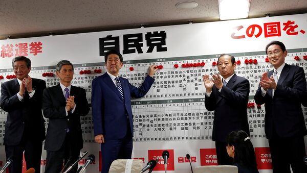 Japan's Prime Minister Shinzo Abe, leader of the Liberal Democratic Party (LDP), puts a rosette on the name of a candidate who is expected to win the lower house election, as his party's lawmakers applaud at the LDP headquarters in Tokyo, Japan October 22, 2017 - Sputnik International