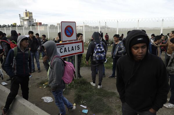 In this Thursday, Oct. 27, 2016 file photo migrants gather near a fence in Calais, northern France.  - Sputnik International