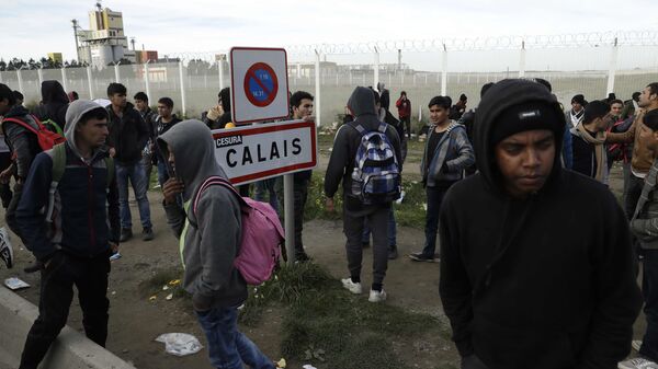 In this Thursday, Oct. 27, 2016 file photo migrants gather near a fence in Calais, northern France. - Sputnik International