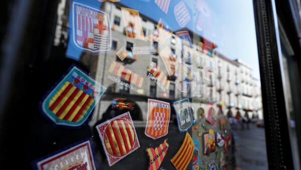 Badges bearing regional flags are sen behind a window reflecting a square in Girona, Spain, October 7, 2017 - Sputnik International