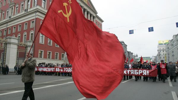 Communist supporter carries the red flag as others carry a banner declaring Long Live the 88th Anniversary of the October Revolution, during the rally to commemorate the Bolshevik Revolution, marking a long-sacred former holiday that was an official working day for the first time in decades in Moscow, Monday, Nov. 7, 2005. - Sputnik International