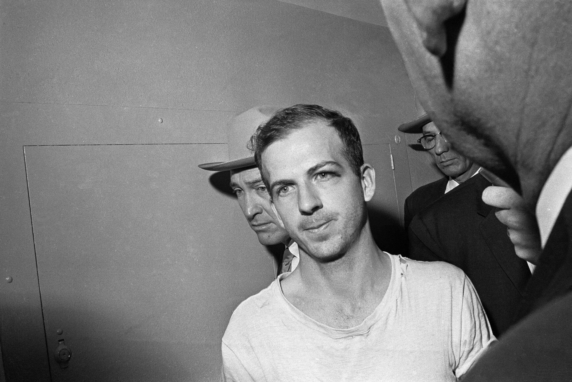 In this Nov. 23, 1963 file photo, Lee Harvey Oswald is led down a corridor of the Dallas police station for another round of questioning in connection with the assassination of US, President John F. Kennedy. Oswald, who denied any involvement in the shooting, was formally charged with murder.  - Sputnik International, 1920, 15.12.2021