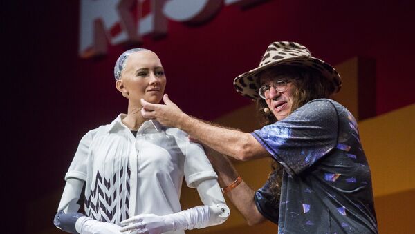 Chief scientist of Hanson Robotics, Ben Goertzel (R), describes to the audience what Sophia the Robot (L) is made of during a discussion about the future of humanity in a demonstration of artificial intelligence (AI) by Hanson Robotics at the RISE Technology Conference in Hong Kong on July 12, 2017 - Sputnik International
