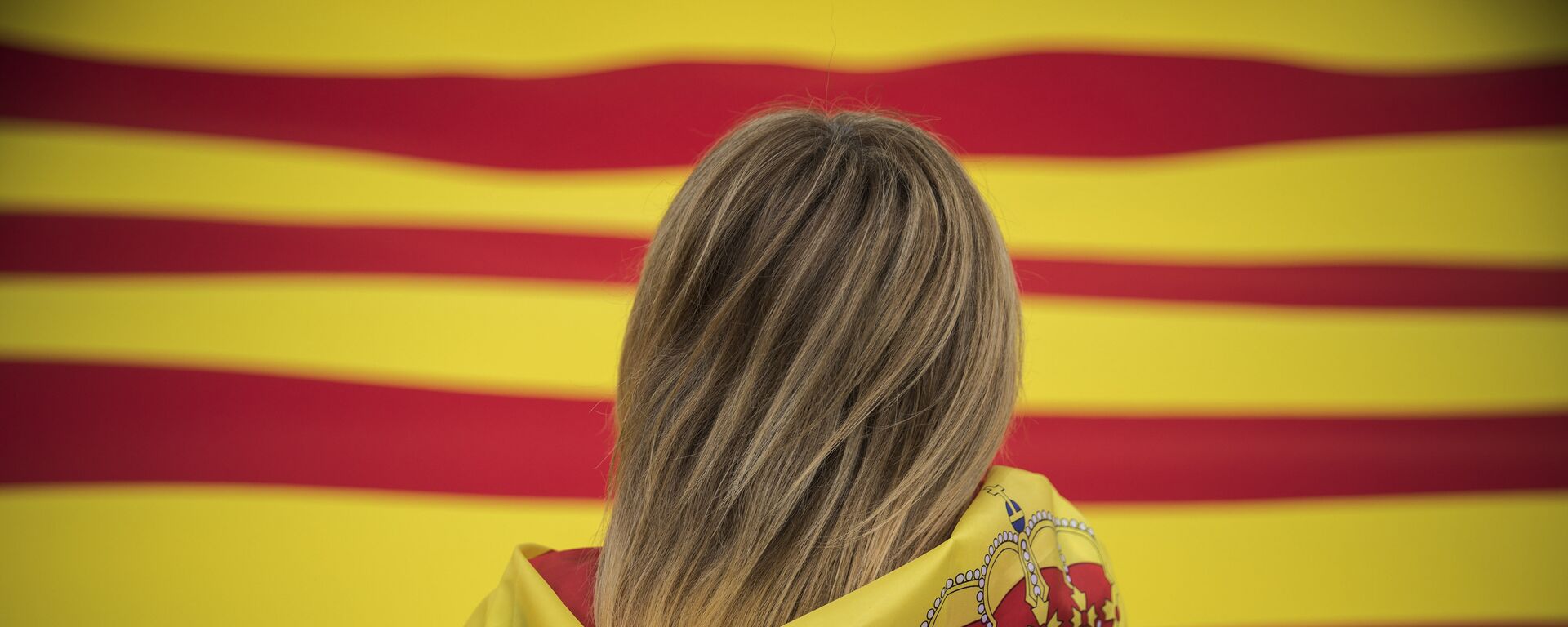 A woman wearing a Spanish flag on her shoulders looks at a giant flag of Catalonia as people celebrate a holiday known as Dia de la Hispanidad or Spain's National Day in Barcelona, Spain, Thursday, Oct. 12, 2017.  - Sputnik International, 1920, 02.02.2023