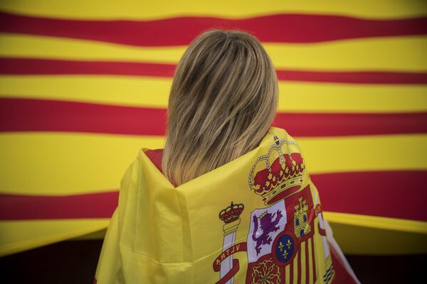 A woman wearing a Spanish flag on her shoulders looks at a giant flag of Catalonia as people celebrate a holiday known as Dia de la Hispanidad or Spain's National Day in Barcelona, Spain, Thursday, Oct. 12, 2017. A woman wearing a Spanish flag on her shoulders looks at a giant flag of Catalonia as people celebrate a holiday known as Dia de la Hispanidad or Spain's National Day in Barcelona, Spain, Thursday, Oct. 12, 2017. - Sputnik International