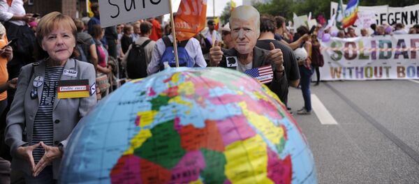 Protesters wear masks of German Chancellor Angela Merkel and US President Donald Trump as they take part in the solidarity without borders instead of G20 demonstration on July 8, 2017 in Hamburg, northern Germany as world leaders meet during the G20 summit Protesters wear masks of German Chancellor Angela Merkel and US President Donald Trump as they take part in the solidarity without borders instead of G20 demonstration on July 8, 2017 in Hamburg, northern Germany as world leaders meet during the G20 summit - Sputnik International