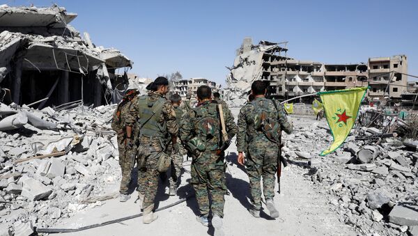 Fighters of Syrian Democratic Forces walk past the ruins of destroyed buildings near the National Hospital after Raqqa was liberated from the Islamic State militants, in Raqqa, Syria October 17, 2017. Picture taken October 17, 2017 - Sputnik International
