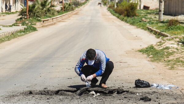 A Syrian man collects samples from the site of a suspected toxic gas attack in Khan Sheikhun, in Syria’s northwestern Idlib province, on April 5, 2017 - Sputnik International