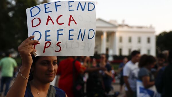 A woman holds up a sign that reads Defend DACA Defend TPS during a rally supporting Deferred Action for Childhood Arrivals, or DACA, outside the White House in Washington, Monday, Sept. 4, 2017 - Sputnik International