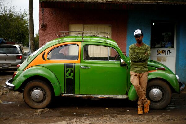 Работник Legendary VW Beetle Gets Unexpected Second Wind in Ethiopiaпозирует рядом со своим восстановленным Volkswagen Beetle - Sputnik International