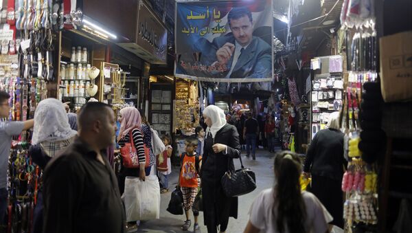 In this May 18, 2017 photo, Syrians shop under a banner showing President Bashar Assad at the Hamadiyah market, in the Old City of Damascus, Syria. - Sputnik International