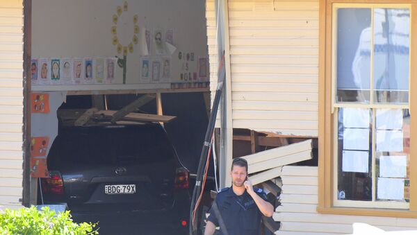 A policeman talks on a phone in front of a vehicle that crashed into a primary school classroom in the Sydney suburb of Greenacre in Australia, November 7, 2017 - Sputnik International