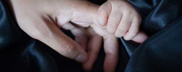 An adult holding a baby's hand An adult holding a baby's hand - Sputnik International