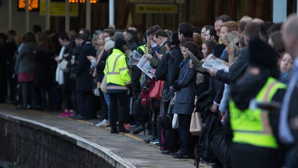 Commuters wait on a platform to catch a train toward central London - Sputnik International