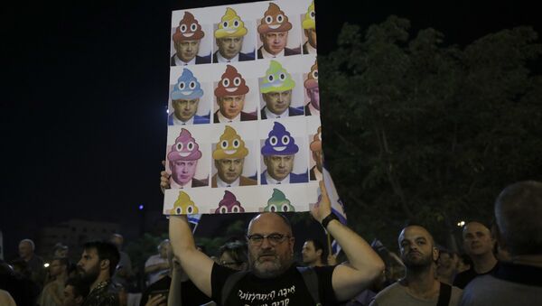 In this Saturday, Aug. 26, 2017 file photo, a man holds up a poster during a weekly protest against Israeli Prime Minister Benjamin Netanyahu, seen on the poster, in front of the home of Israel's attorney general Avichai Mandelblit, in Petah Tikva, Israel. With a slew of corruption scandals closing in on him, Netanyahu is increasingly dropping what remains of his statesmanlike persona in favor of nationalist rhetoric popular with his base. By cozying up to conservatives, anti-migrant voices and West Bank settlers, Netanyahu appears to be trying to reframe the corruption allegations as an ideological witch-hunt. - Sputnik International
