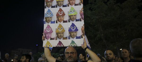 In this Saturday, Aug. 26, 2017 file photo, a man holds up a poster during a weekly protest against Israeli Prime Minister Benjamin Netanyahu, seen on the poster, in front of the home of Israel's attorney general Avichai Mandelblit, in Petah Tikva, Israel. With a slew of corruption scandals closing in on him, Netanyahu is increasingly dropping what remains of his statesmanlike persona in favor of nationalist rhetoric popular with his base. By cozying up to conservatives, anti-migrant voices and West Bank settlers, Netanyahu appears to be trying to reframe the corruption allegations as an ideological witch-hunt. - Sputnik International