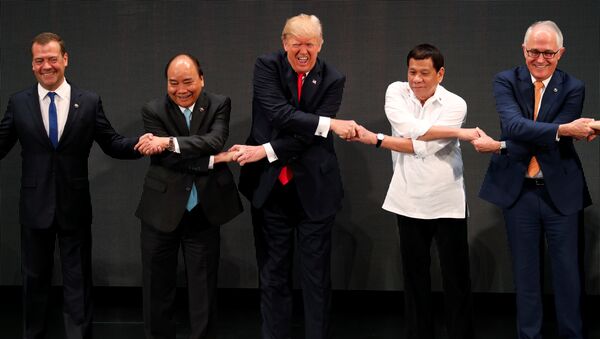 U.S. President Donald Trump smiles with other leaders, including Russia's Prime Minister Dmitry Medvedev, Vietnam's Prime Minister Nguyen Xuan Phuc, President of the Philippines Rodrigo Duterte and Australia's Prime Minister Malcolm Turnbull, as they cross their arms for the traditional ASEAN handshake in the opening ceremony of the ASEAN Summit in Manila, Philippines November 13, 2017 - Sputnik International