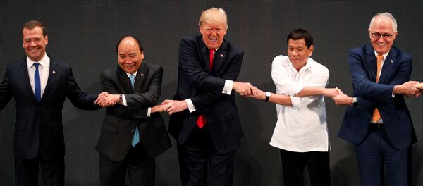 U.S. President Donald Trump smiles with other leaders, including Russia's Prime Minister Dmitry Medvedev, Vietnam's Prime Minister Nguyen Xuan Phuc, President of the Philippines Rodrigo Duterte and Australia's Prime Minister Malcolm Turnbull, as they cross their arms for the traditional ASEAN handshake in the opening ceremony of the ASEAN Summit in Manila, Philippines November 13, 2017 - Sputnik International