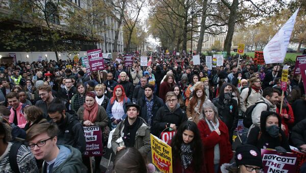 Demonstrators hold up placards at a protest march through central London on November 19, 2016 called by the National Union of Students and University College Union to demand free, quality further and higher education, accessible to all - Sputnik International