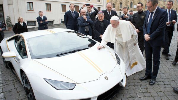 Pope Francis writes on the bonnet of a Lamborghini donated to him by the luxury sports car maker, at the Vatican - Sputnik International