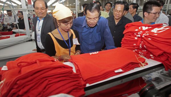 Cambodian Prime Minister Hun Sen, center, leans over a garment worker - Sputnik International