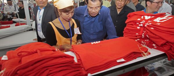 Cambodian Prime Minister Hun Sen, center, leans over a garment worker Cambodian Prime Minister Hun Sen, center, leans over a garment worker - Sputnik International