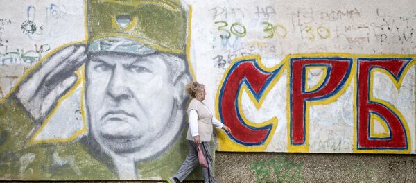 A woman walks past a graffiti depicting former Bosnian Serb commander Ratko Mladic and reading Serbia written in Cyrillic, painted on a wall in Belgrade on Nocember 22, 2017. - Sputnik International