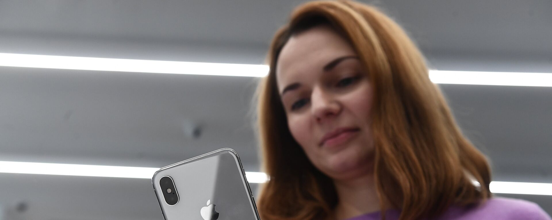 A buyer examines a new smartphone iPhone X in re:Store mobile equipment store on Tverskaya Street in Moscow - Sputnik International, 1920, 01.06.2023